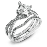 This dramatic white gold engagement ring and wedding band set are highlighted by .23 ctw of dazzling round cut white diamonds in a distinctive modern twist design.
