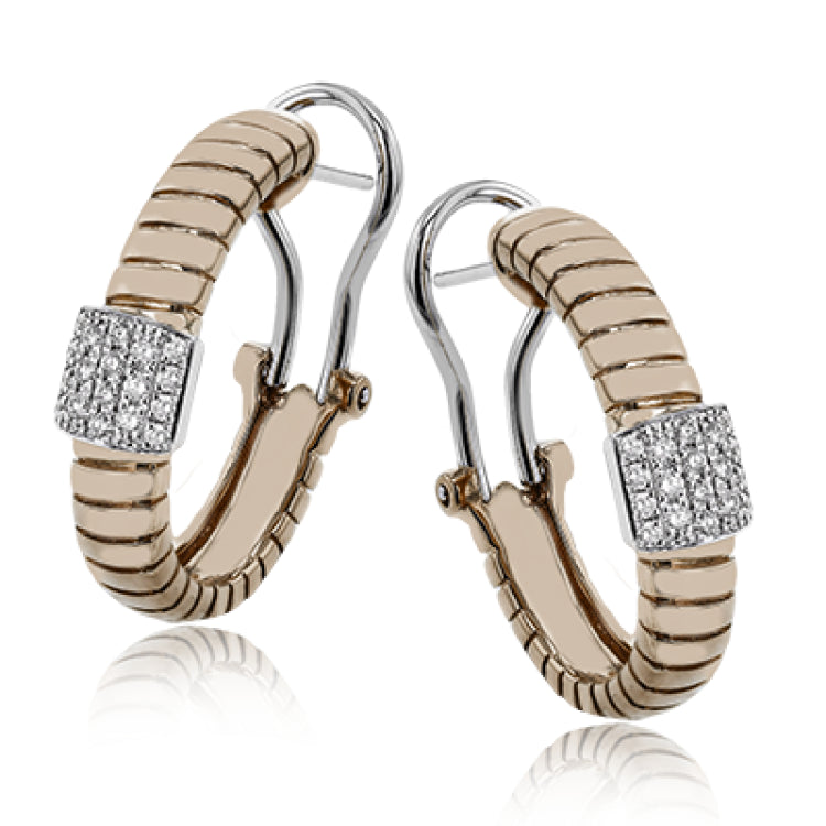 This elegant huggie earring in 18K yellow gold has a ribbed design and accented with 0.24 ctw. of pave set diamonds in white gold, and a lever back closure