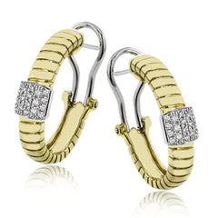 This elegant huggie earring in 18K yellow gold has a ribbed design and accented with 0.24 ctw. of pave set diamonds in white gold, and a lever back closure