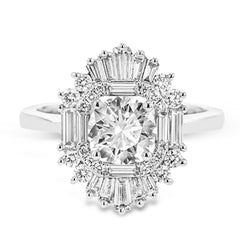 Crafted in 18K white gold, this distinctive ring is an ode to Art Deco design & features a halo of RD diamonds 0.23 ctw, surrounded by a burst of baguette shaped diamonds 0.70 ctw.