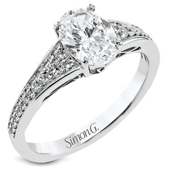 This white gold engagement ring takes an oval center stone and has a tapered shank, with diamonds .22 ctw graduating in size down the sides. On the profile there is hand carved filligree design.