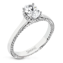 This engagement ring is made from an oval center stone and features a low halo as well as diamonds extended down the sides of the ring.