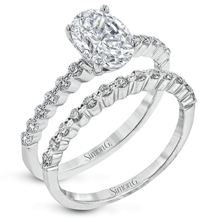 This contemporary wedding set features .48 ctw of diamond side stones and is designed to perfectly showcase an oval center stone.