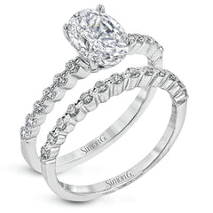 This contemporary wedding set features .48 ctw of diamond side stones and is designed to perfectly showcase an oval center stone.