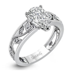A delicate floral design highlights this vintage style engagement ring accented by .09 ctw of shimmering round cut white diamonds.