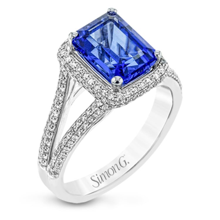 This splendid white gold ring features a delicate split shank and halo, set with .46 ctw of round white diamonds, framing a lovely 2.71 ctw emerald cut tanzanite.