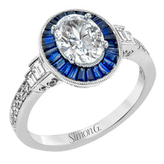 This remarkable ring features milgrain edging and .75 ctw of baguette shaped sapphires in its halo, flanked by .11 ctw of round white diamonds and .16 ctw of baguette shaped white diamonds.