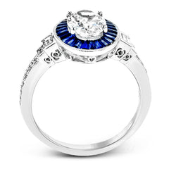 This remarkable ring features milgrain edging and .75 ctw of baguette shaped sapphires in its halo, flanked by .11 ctw of round white diamonds and .16 ctw of baguette shaped white diamonds.