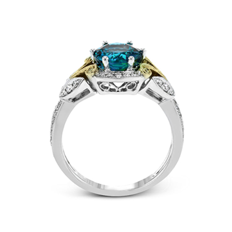 This two-toned vintage inspired right hand ring features a blue zircon center 3.11 ctw. surrounded by white diamonds 0.25 ctw and accented by natural yellow diamonds set in a yellow gold filigree detail.