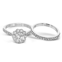 This white gold wedding set frames its centerpiece with .90 ctw of round white diamonds in a whimsical floral-inspired design.