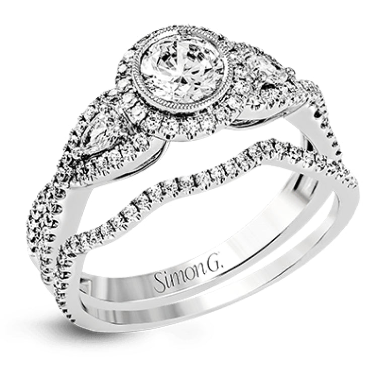 This 18k white gold wedding set has a distinctive design with a milgrain accented bezel center stone setting, .15 ctw pear side stones, and .50 ctw of round brilliant diamonds.