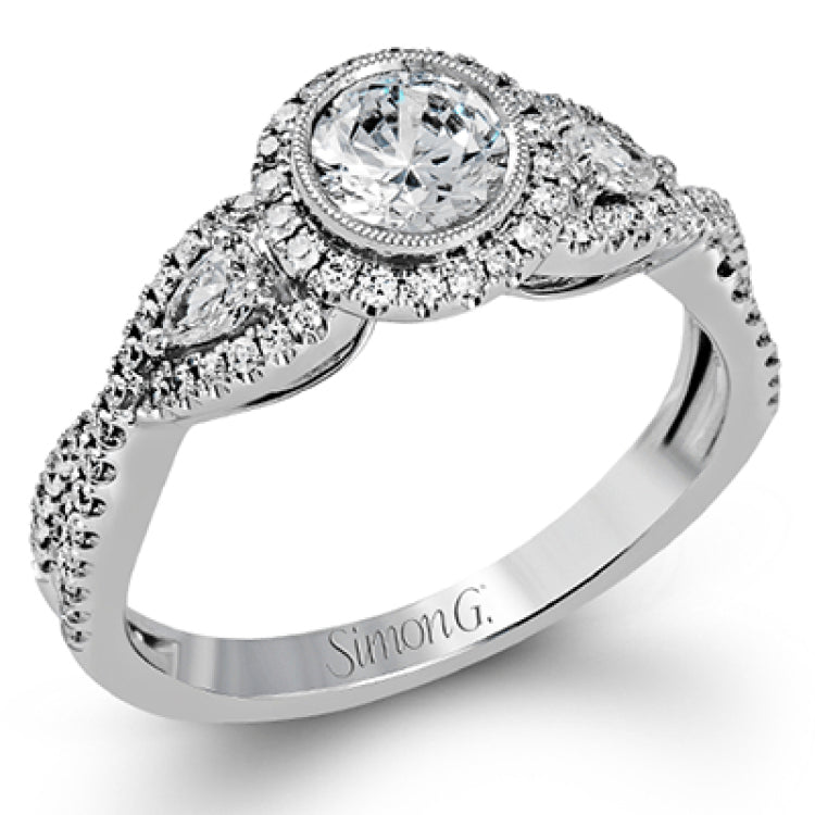 This 18k white gold wedding set has a distinctive design with a milgrain accented bezel center stone setting, .15 ctw pear side stones, and .50 ctw of round brilliant diamonds.