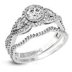 This 18k white gold wedding set has a distinctive design with a milgrain accented bezel center stone setting, .15 ctw pear side stones, and .50 ctw of round brilliant diamonds.
