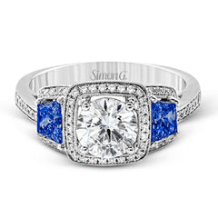Featuring an elegant classic design, this white gold engagement ring is set with .23 ctw round cut white diamonds and side accents of .62 ctw trapezoid cut sapphires.