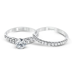 Elevating a classic design with modern elements, this exquisite white gold engagement ring and band are emphasized by .77 ctw of sparkling round cut white diamonds.