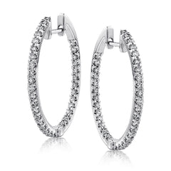 Featuring a classic hoop style, these white gold earrings are accented with .85 ctw of gleaming round cut white diamonds.