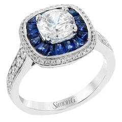 Specially shaped sapphires formed a halo around the center stone in this remarkable engagement ring, accented by .42 ctw of white diamonds as well.
