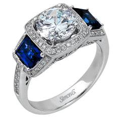 Featuring an elegant classic design, this white gold engagement ring is set with .23 ctw round cut white diamonds and side accents of .62 ctw trapezoid cut sapphires.
